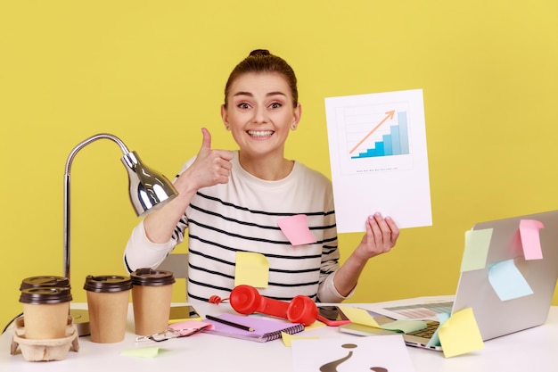 Happy woman office manager looking at camera showing growth diagram financial and economic growth