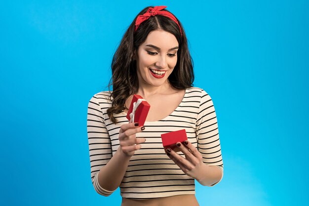 The happy woman opening the gift box on the blue background