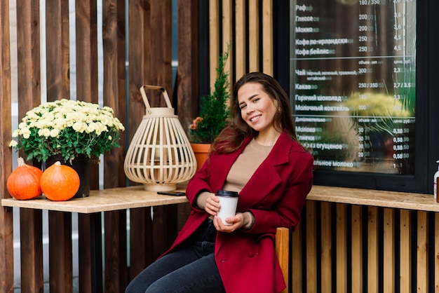 Donna felice al caffè all'aperto che beve e sorride