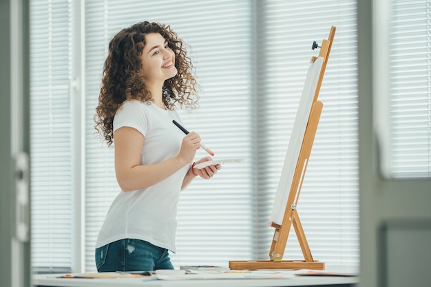 The happy woman painting a picture on the easel