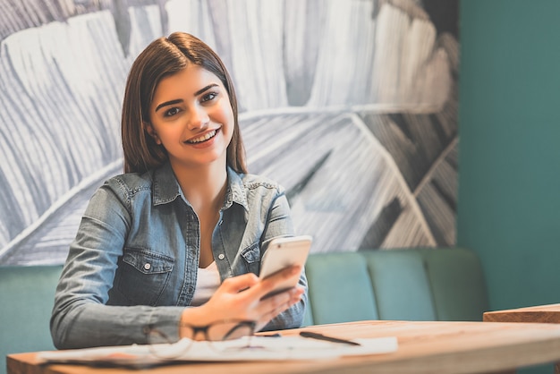 The happy woman phones at the table in a cafe