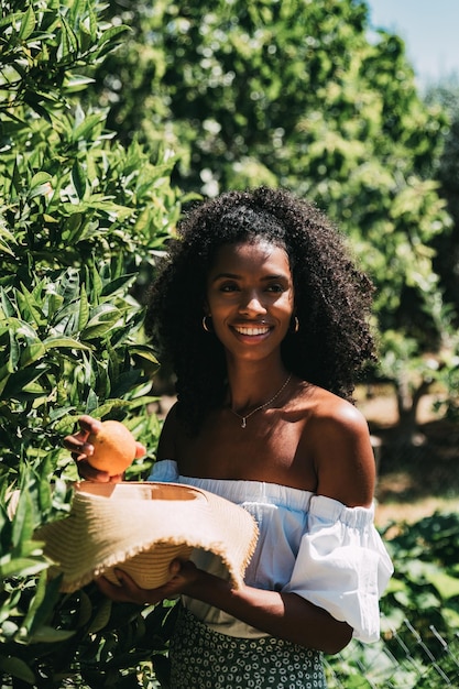 Happy woman picking orange fruit in garden