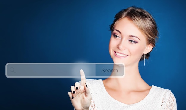 Happy woman pointing to empty address bar in virtual web browser on blue background