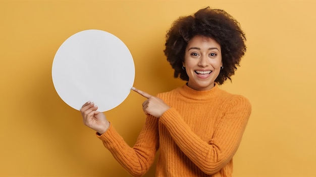Happy woman pointing at white blank circular frame over yellow background