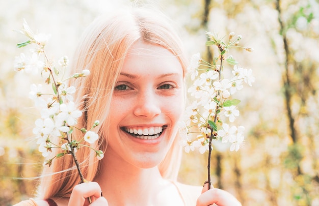 Happy woman portrait close up. Spring border background with white blossom. Woman on branch delicate spring flowers.