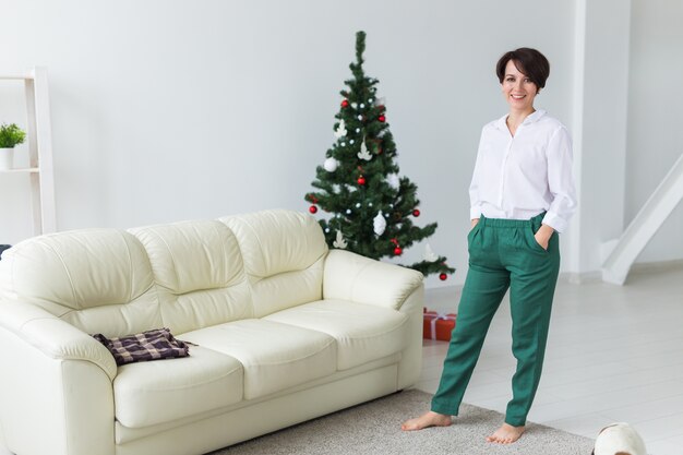 Happy woman posing next to the Christmas tree