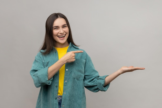 Happy woman presenting copy space on her palm showing empty place for commercial text or goods