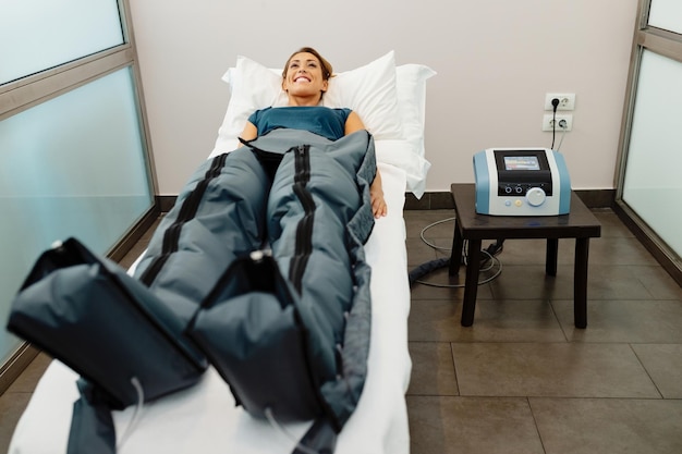 Happy woman during pressotherapy treatment at health spa
