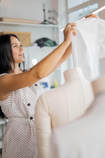 縫製スタジオで働くマネキンのティッシュパターンを試して幸せな女性のプロの仕立て屋