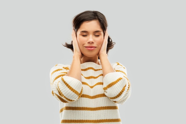 Photo happy woman in pullover closing ears by hands