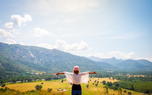 Photo happy woman raised her arms up on top of mountain
