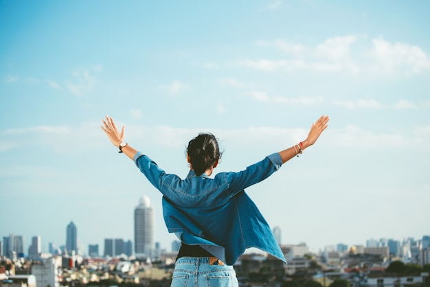 Photo happy woman raising hands in the city scene background with copy space