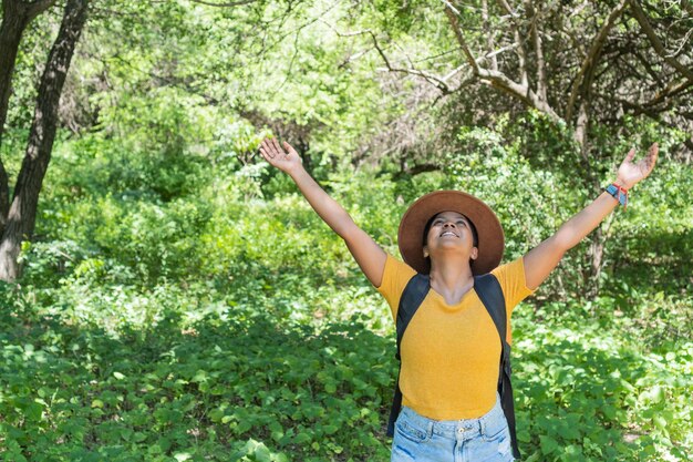 Happy woman raising her hands in the forest