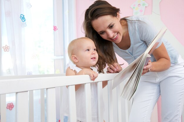 かわいい赤ちゃんに本を読んでいる幸せな女性