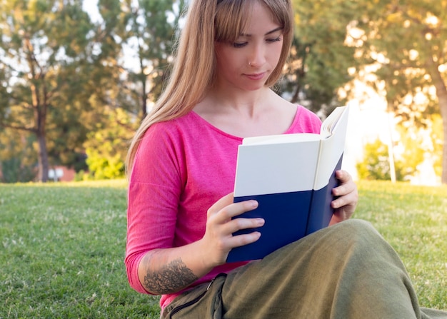 Happy woman reading a book in the park