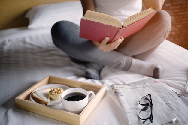 Happy woman reading a book and relaxing comfortably at home.