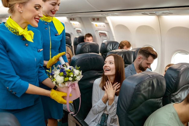 Happy woman receiving gifts from stewardesses in airplane