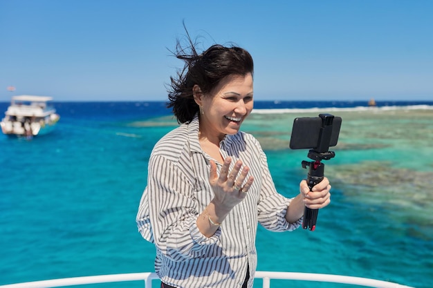 스마트폰 배경에서 비디오 스트림을 녹화하는 행복한 여성은 다이빙과 스노클링을 위한 장소입니다.