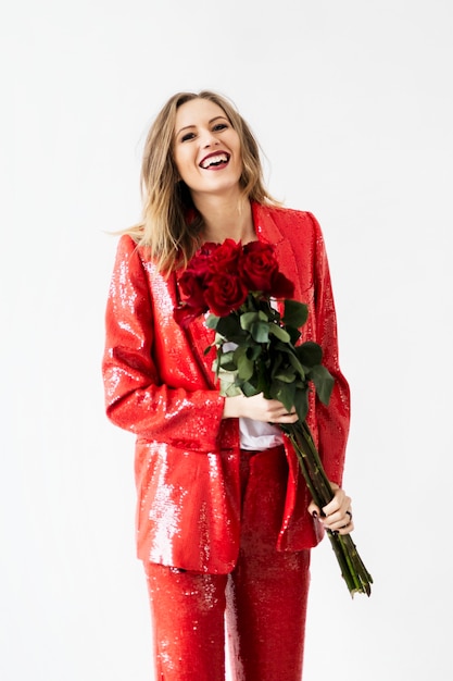 Happy woman in a red pantsuit with a bouquet of roses