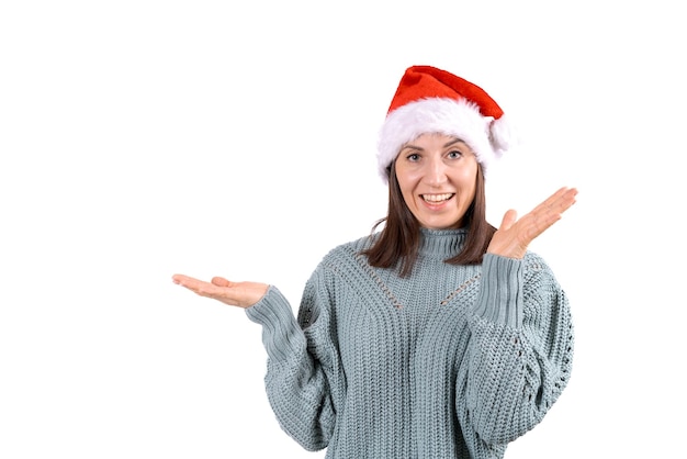 Happy woman in red santa claus hat shows with hands to the side copy space