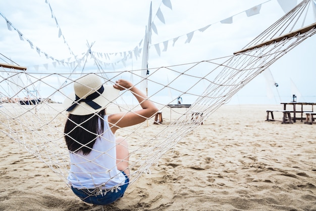 Happy woman relax in hammock on beach