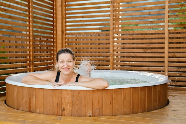 Foto donna felice che si rilassa nella vasca calda.