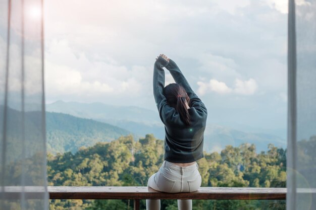 아침 휴가 블로거 SoloTravel 여행 및 편안한 개념에서 시골 집이나 홈스테이에서 휴식을 취하고 산 전망을 바라보는 행복한 여성