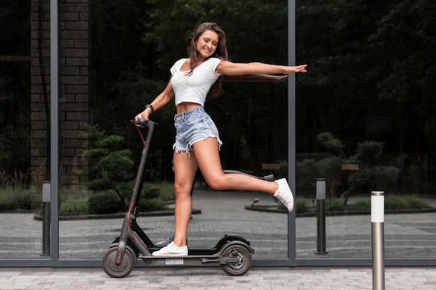 Foto donna felice che guida scooter elettrico all'aperto