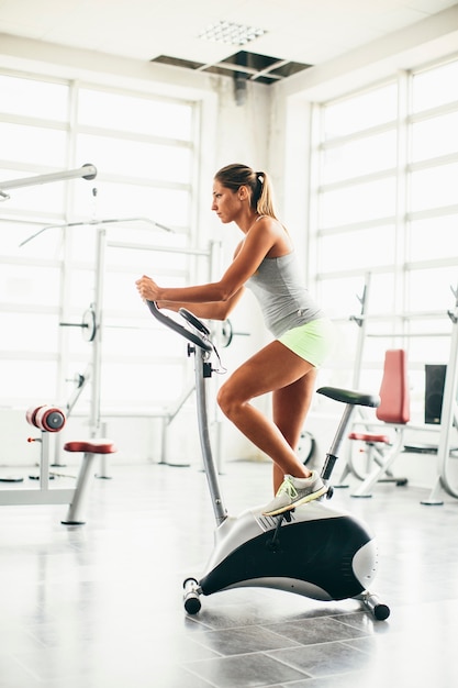 Happy woman riding an exercise bike in gym