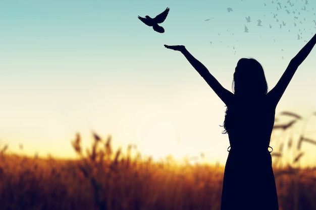 Happy woman rise hand and birds on sky background