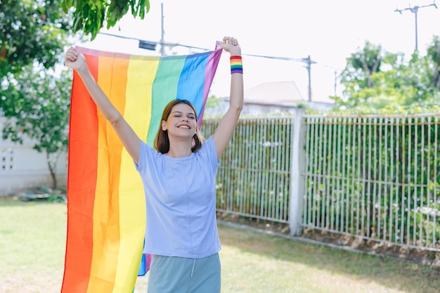 Happy woman rising rainbow flag for support LGBT transgender homosexual equality rights campaign activity