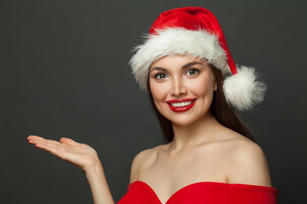 Photo happy woman santa holding empty open hand on black christmas holiday and new year party background