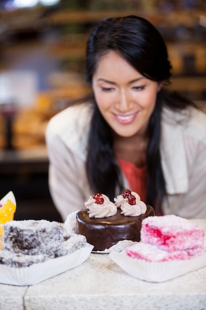 Happy woman selecting desserts from display