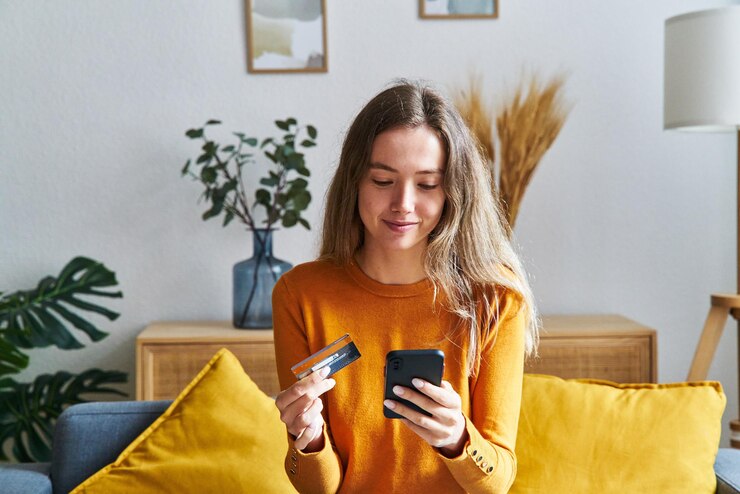 Photo happy woman shopping online with credit card and cell phone at home