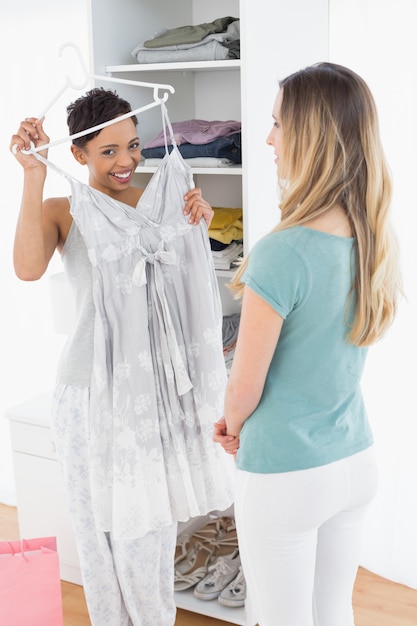 Happy woman showing a dress to her friend