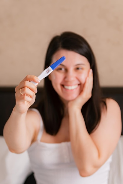 happy woman showing positive pregnancy test close up