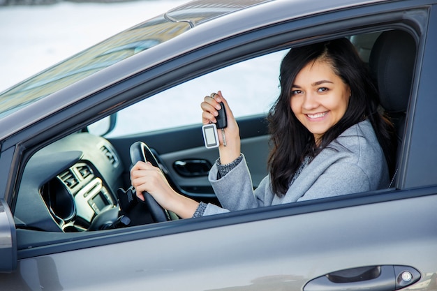 幸せな女は、新しい車からの鍵を示しています。