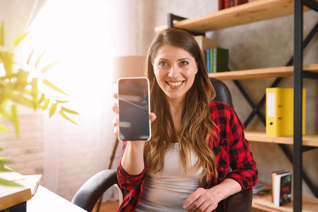 Happy woman shows something in her modern smartphone