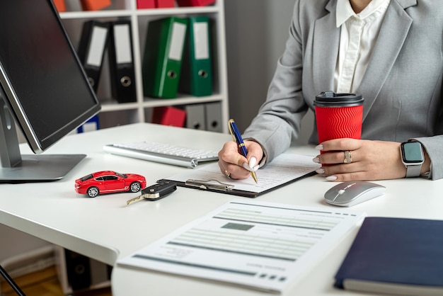 幸せな女性はオフィスで新しい車を購入したり車をレンタルしたりする契約書の融資契約書に署名します