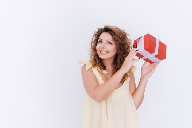 Happy woman in singlet with gift in hands looking up. Isolated gray wall