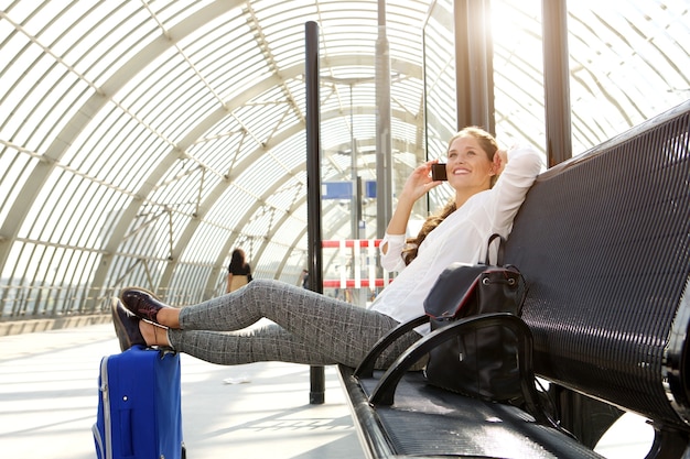 Photo happy woman sitting on bench talking on mobile phone