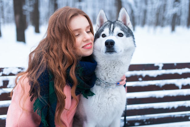 Happy woman sitting on the bench with husky