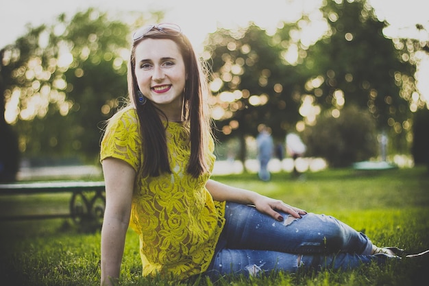 Happy woman sitting on the grass in the evening