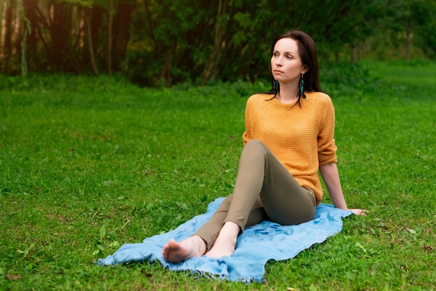 Счастливая женщина, сидя на траве в парке отдыха