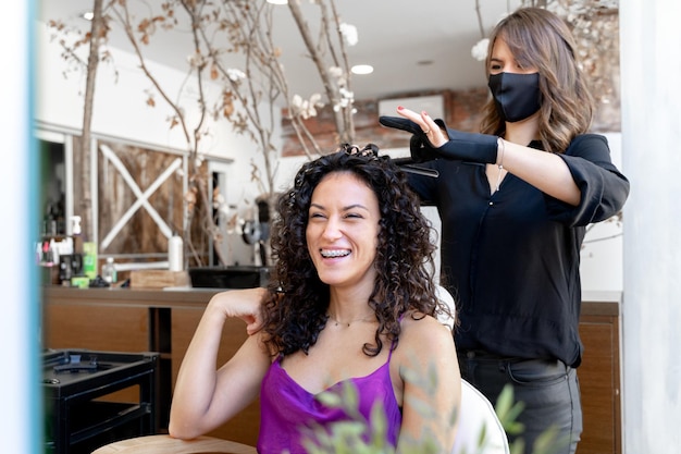 Photo happy woman sitting in a hairdresser salon while being attended