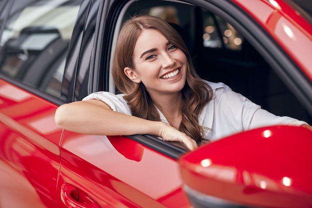 新しい自動車に座っている幸せな女性