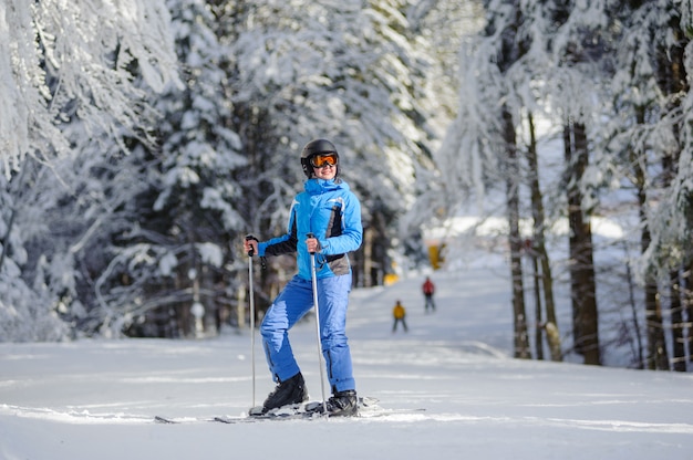 Happy woman skier on a ski slope in the forest