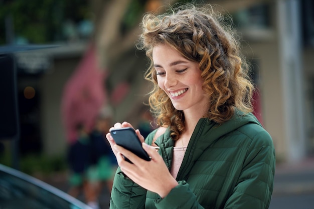 Photo happy woman smile and typing on phone during travel in city using social media internet and 5g network connection outside young female flirting on a mobile app for communication on urban street