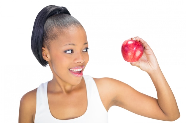 Happy woman in sportswear looking at red apple