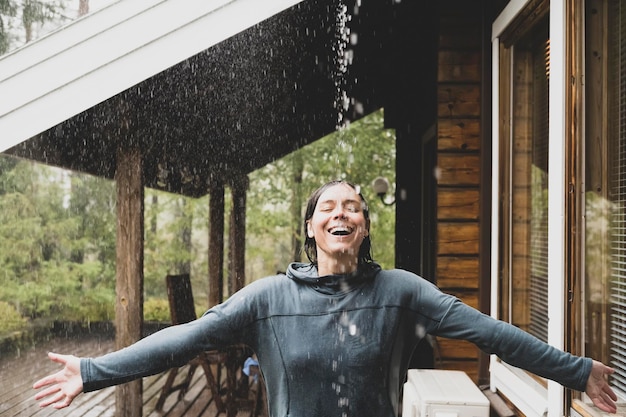 Photo happy woman spread her arms to the side and enjoying the warm rain